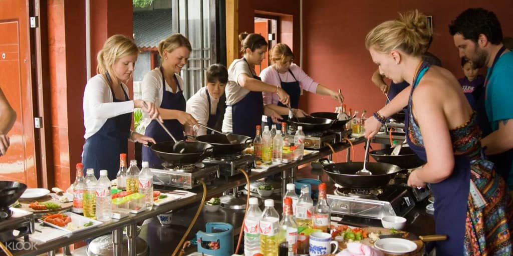 A group of tourists participating in a food tour in Lima, Peru. People cooking together in a traditional cooking class, using woks and fresh ingredients such as vegetables and spices. A fun and educational experience to learn how to prepare typical Peruvian dishes in a warm and welcoming environment.